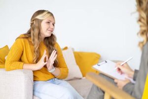 woman in yellow shirt talks with therapist about a motivational interviewing program